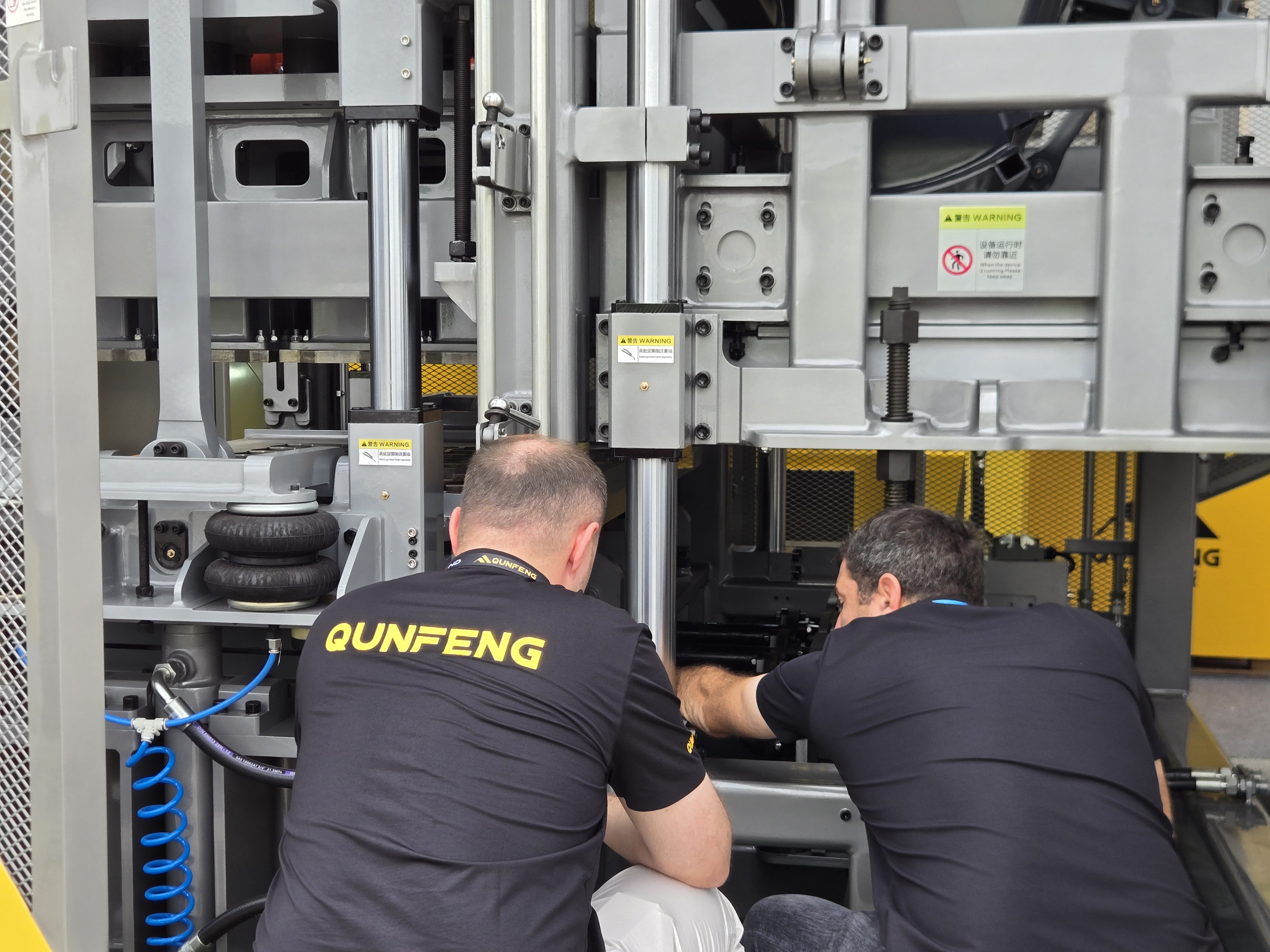 A Russian client carefully examines the details of Qunfeng Machinery equipment. Um cliente russo examina cuidadosamente os detalhes do equipamento da Qunfeng Machinery.