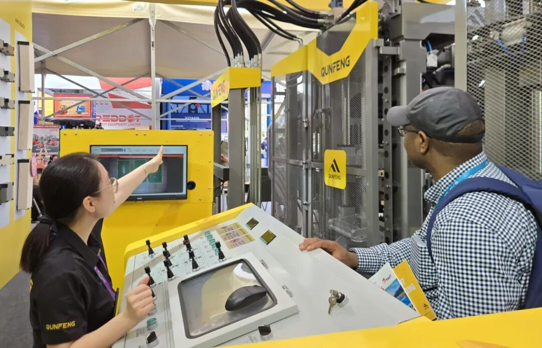 Compradores africanos analisando m&aacute;quinas de fabrica&ccedil;&atilde;o de blocos Qunfeng para projetos de infraestrutura local